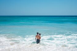 kid holding kid walking into ocean